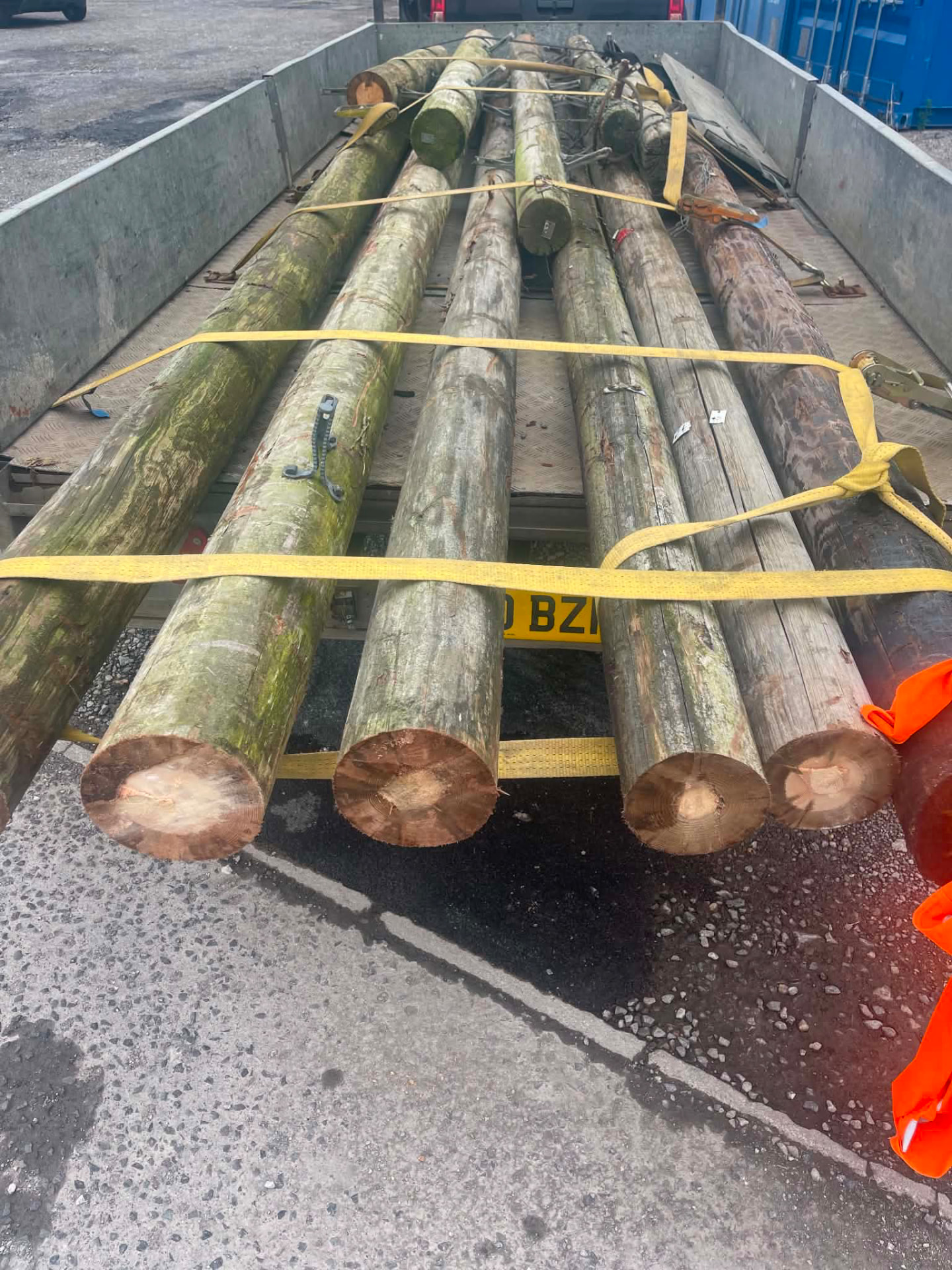 Reclaimed timber poles strapped to a trailer ready for transport
