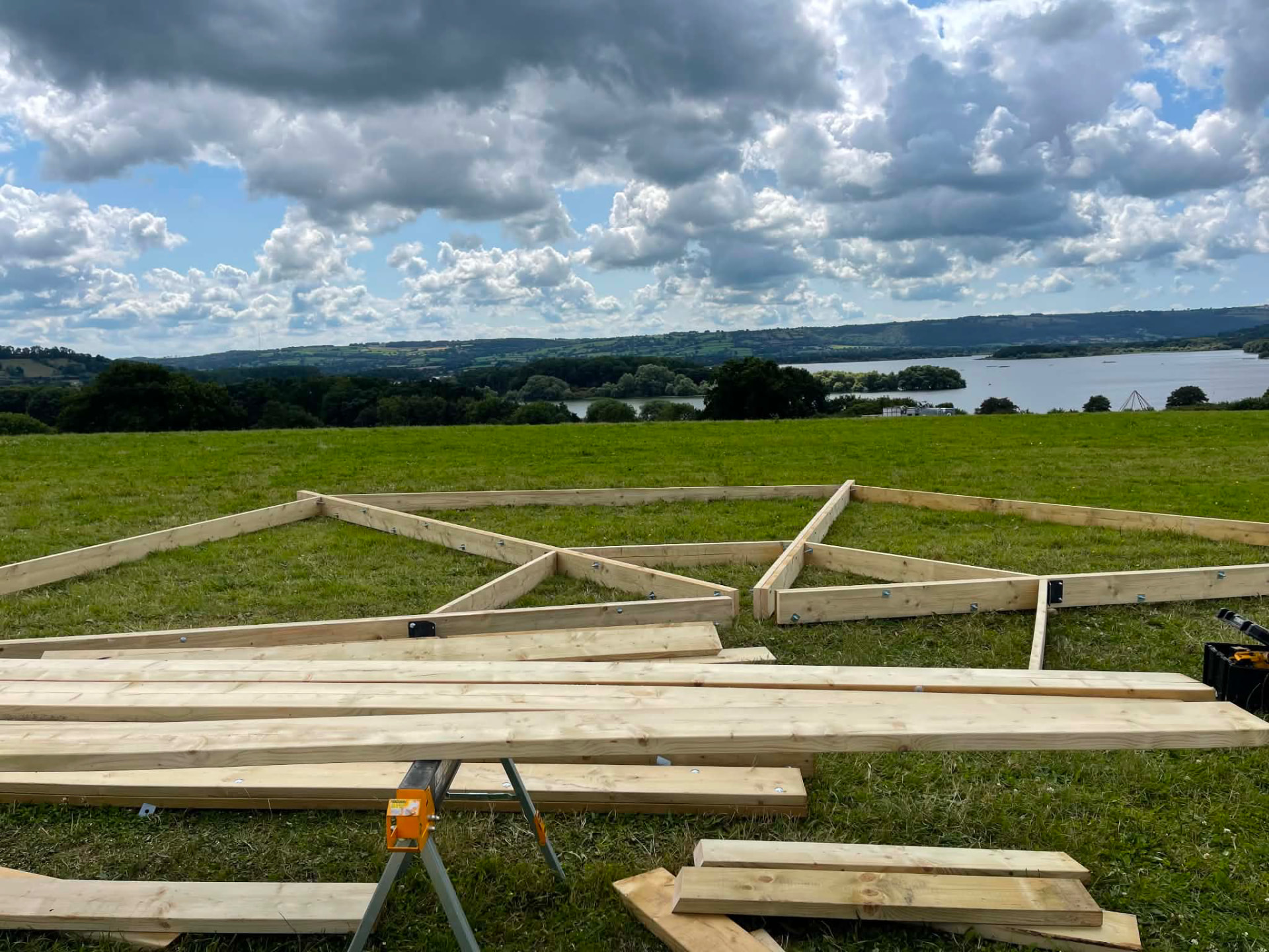 Timber frame sections laid out on site overlooking Chew Valley Lake